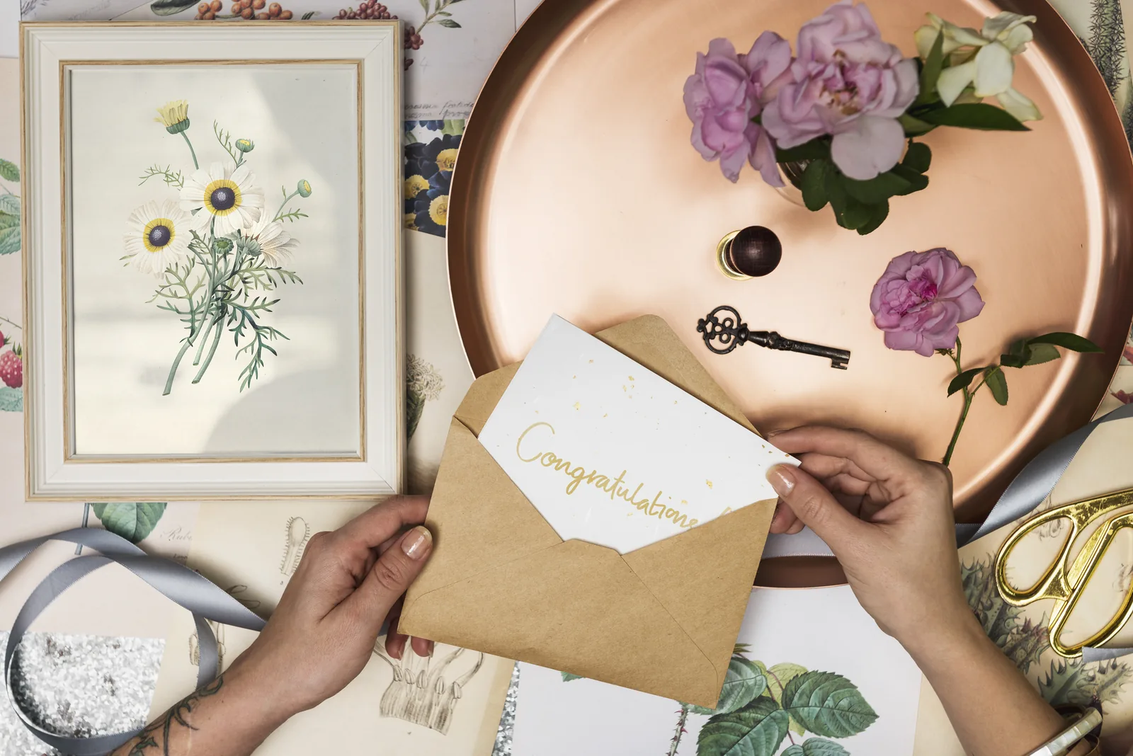 Gold Congratulations card tucked into a kraft envelope with roses and vintage props