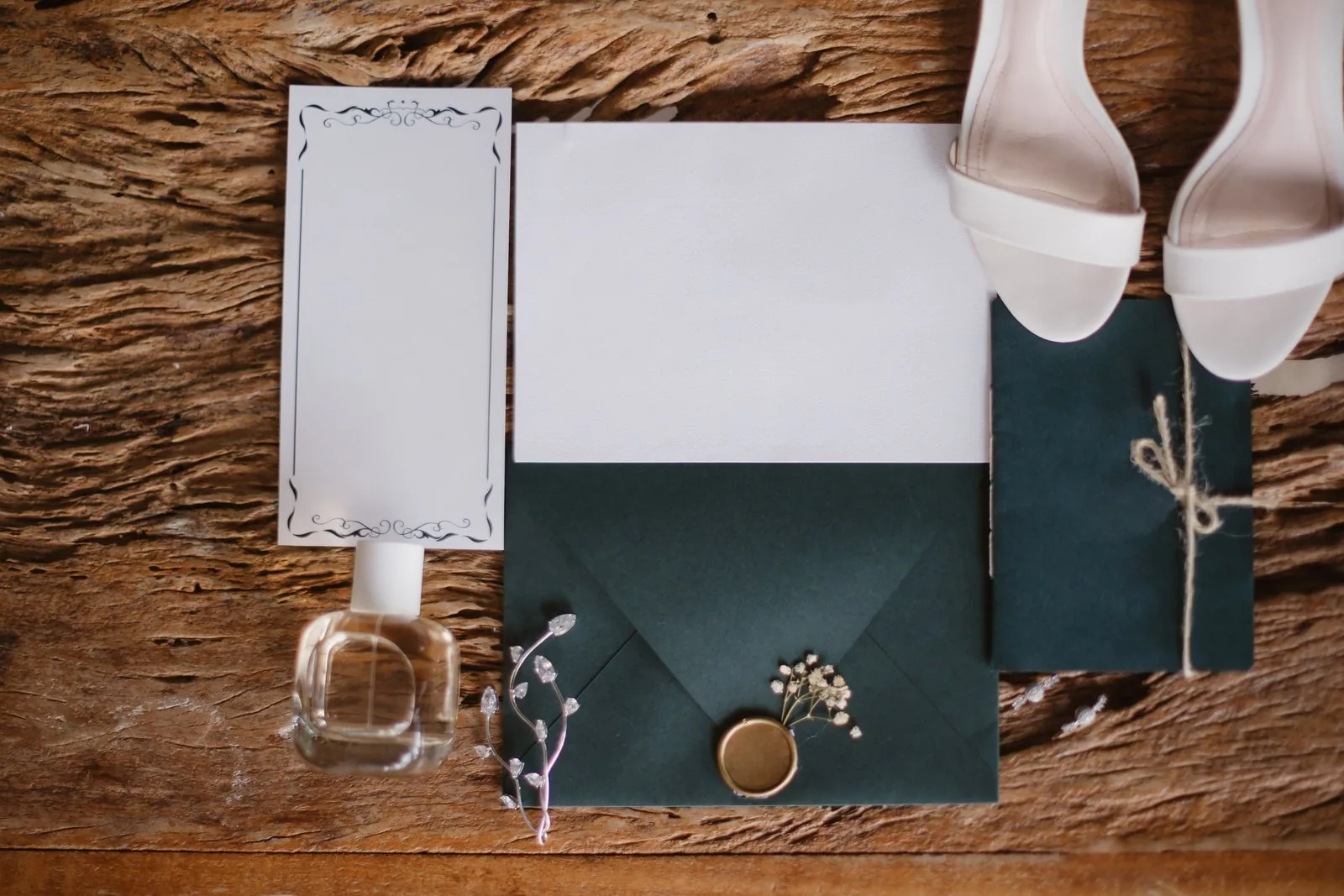 Wedding invitation suite laid flat with a dark green envelope, blank cards, and a wax seal