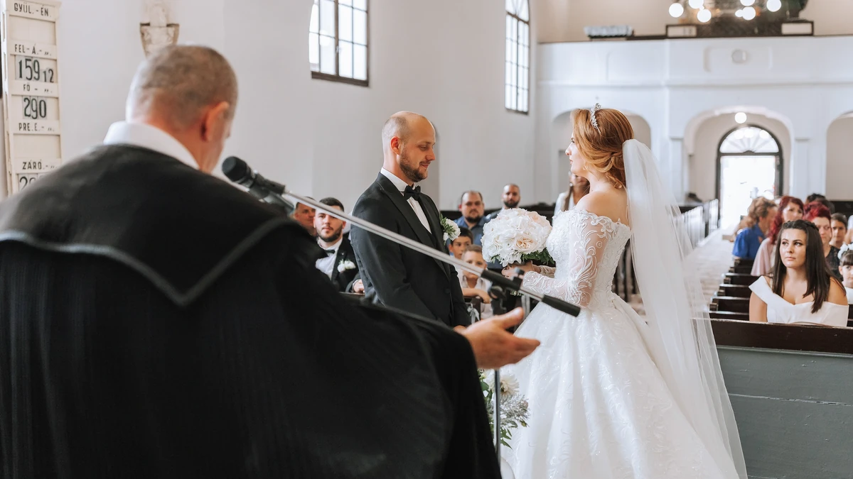 Bride and groom standing before a robed minister at a church altar as guests look on from the pews