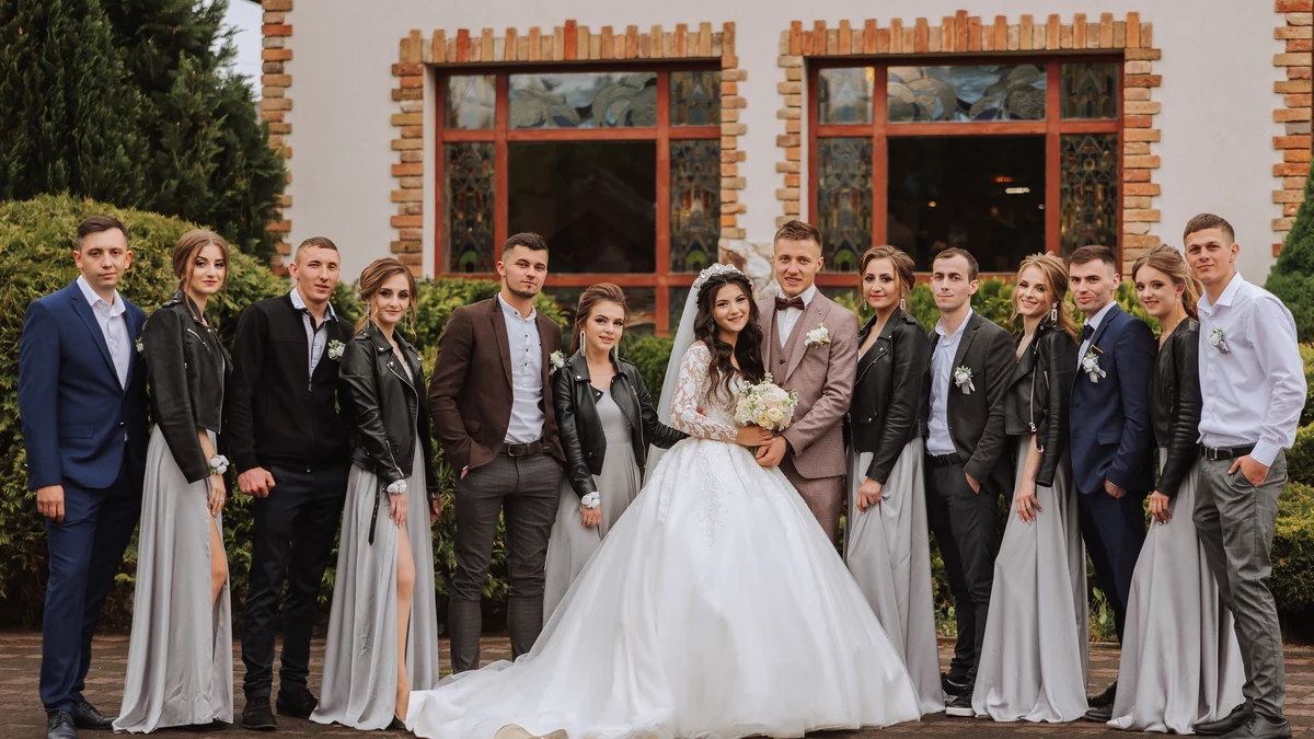 Bride, groom, bridesmaids and groomsmen laughing together outdoors after the wedding ceremony