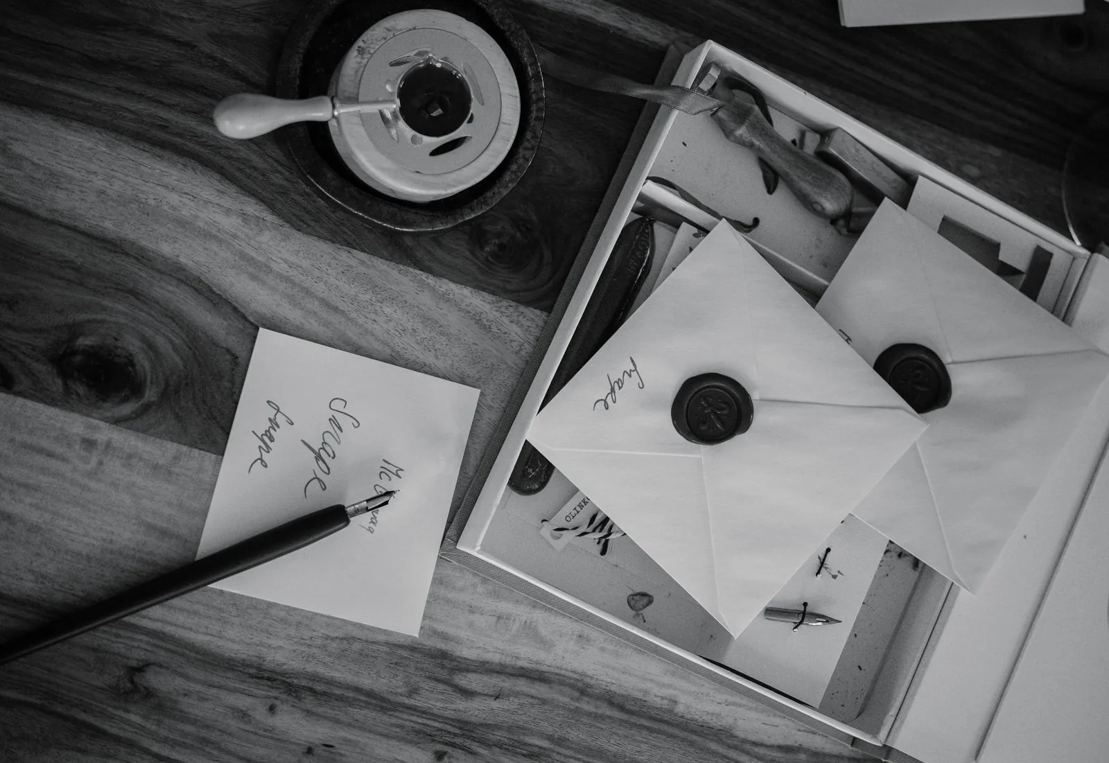 Calligraphy pen, ink, and hand-addressed envelopes on a wooden desk