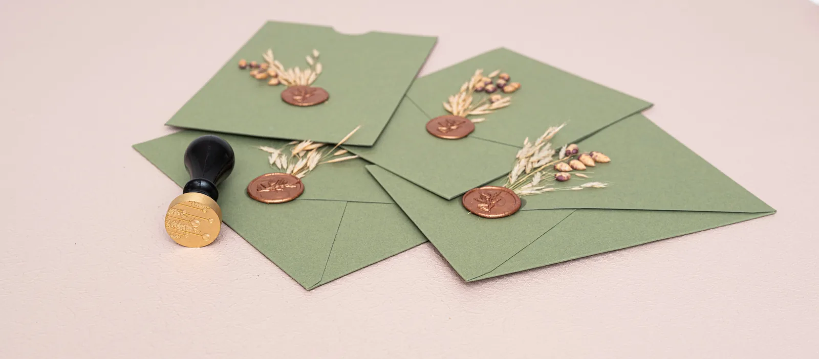 Sage green wedding invitation envelopes with wax seals and dried florals