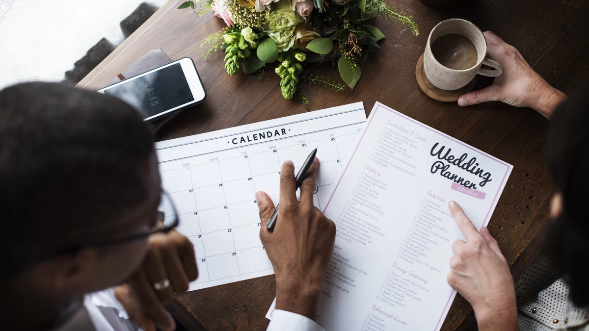 Couple marking a date on a calendar beside a wedding planner checklist listing RSVP cards