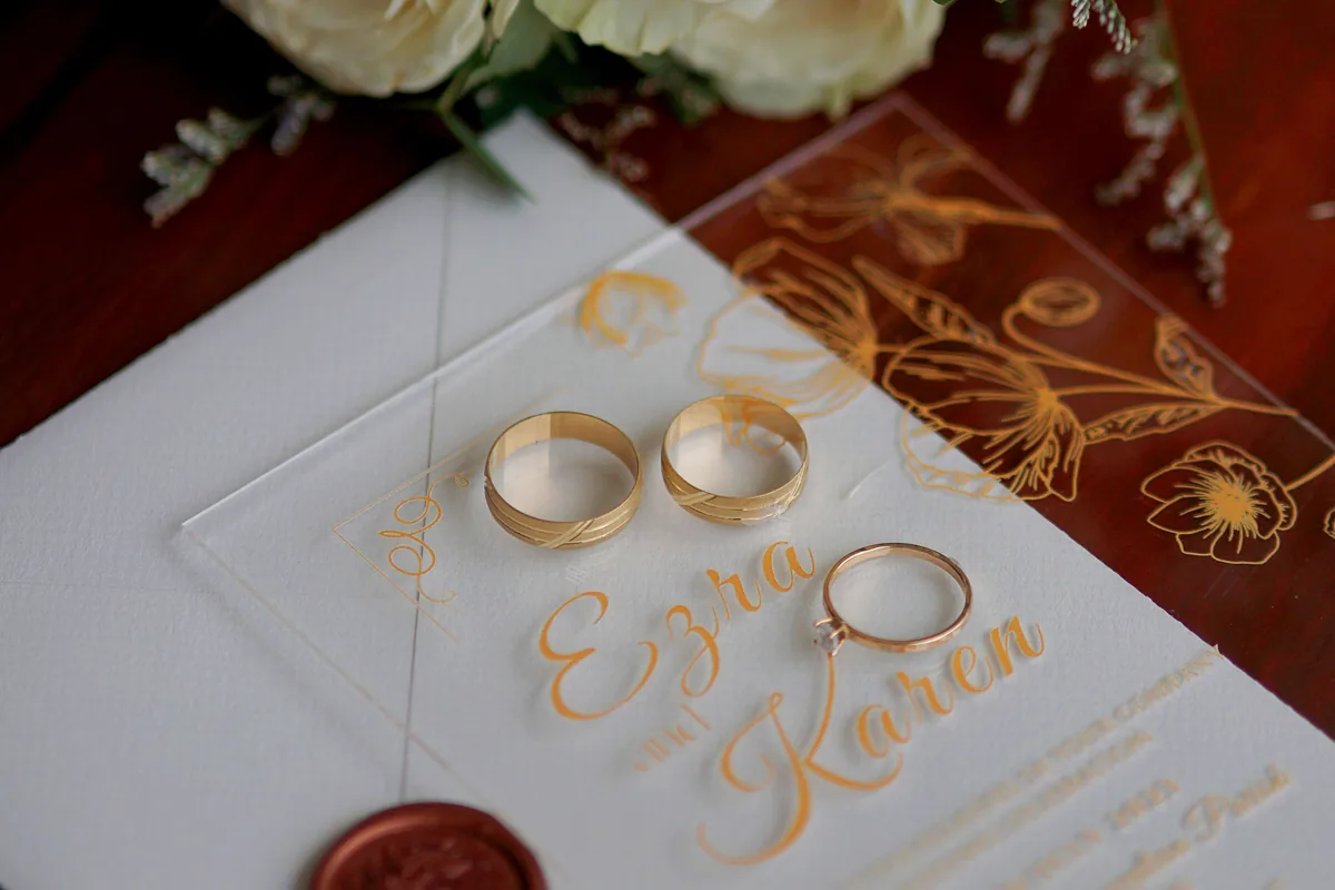 Wedding invitation host line naming both sets of parents alongside the phrase with their families, including a late parent represented by a relative, showing how to word the host line when families are hosting together