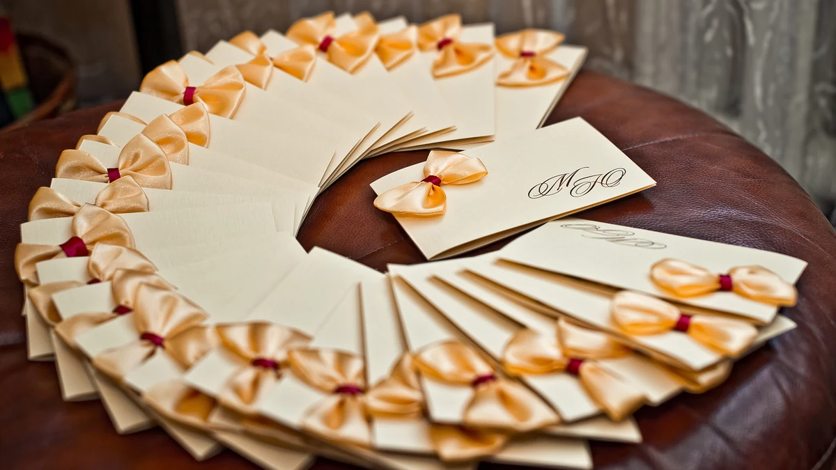 Fan of cream monogrammed wedding envelopes finished with peach satin bows