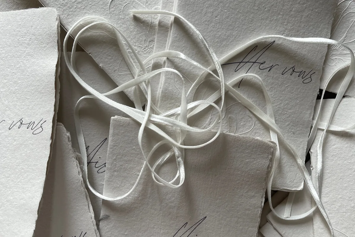 Handmade paper wedding vow cards with deckled edges and silk ribbon, an example of relaxed informal wedding stationery