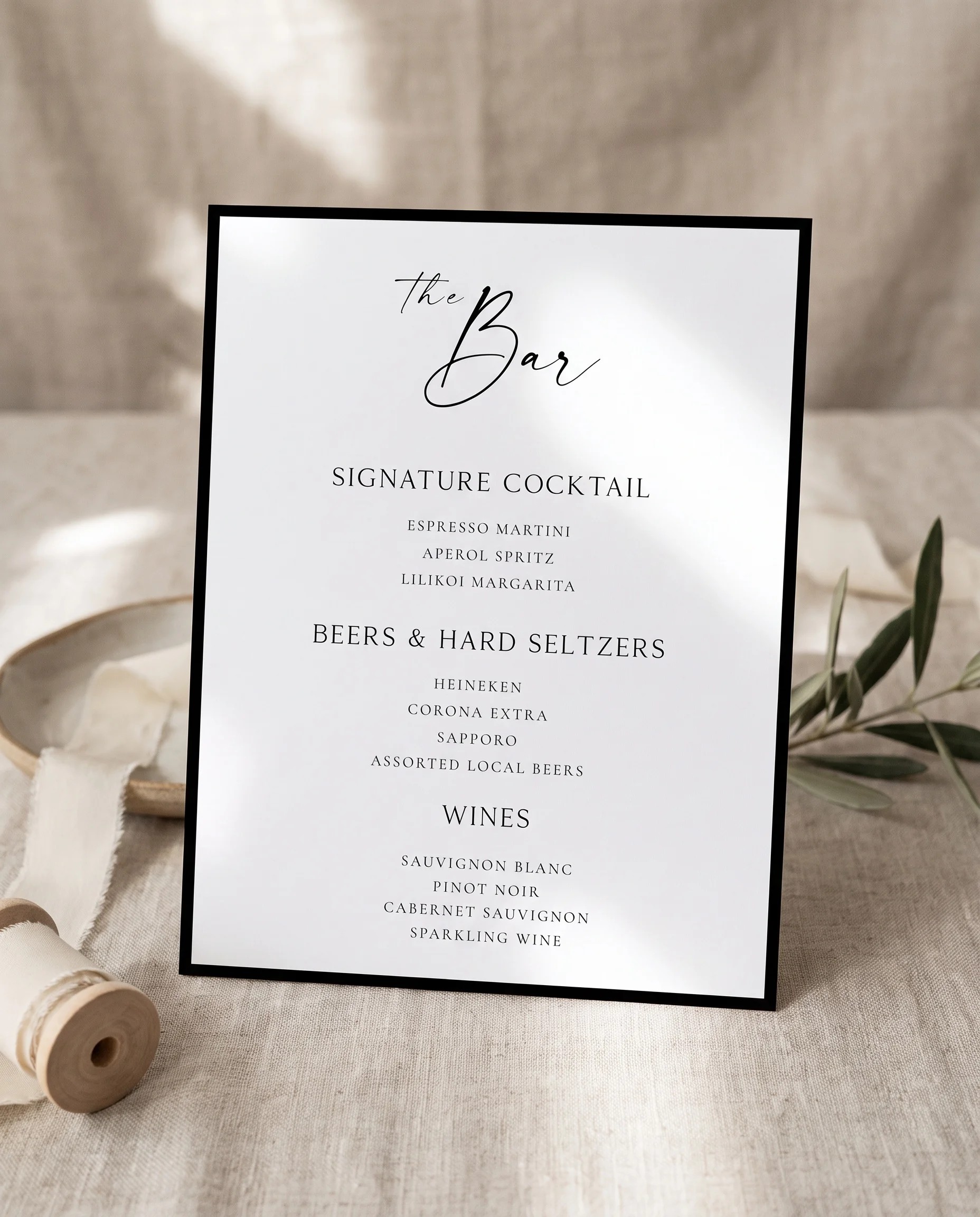 Lumen Frame — bar menu page displayed upright in a styled setting under soft natural light, wedding bar sign.