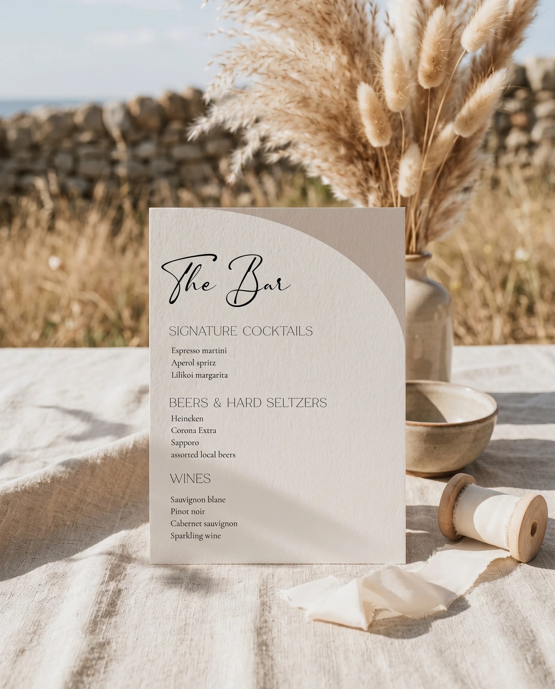 Tassel Arc — bar menu page displayed upright on premium editorial paper under soft natural light at a slight overhead angle, wedding bar sign.