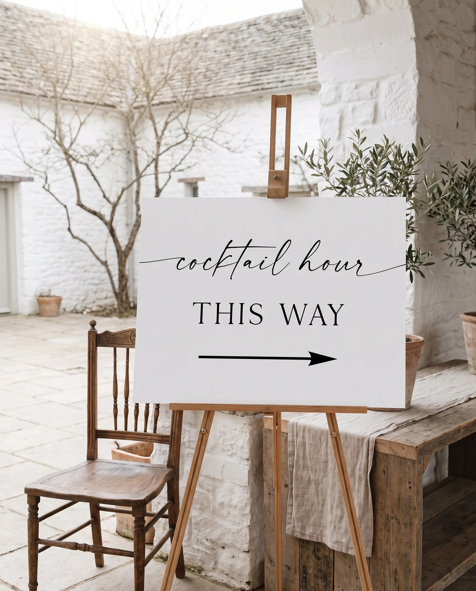 Liminal wedding cocktail hour sign — shown beside furniture for scale, photographed at a slight overhead angle in soft natural light, wedding signage.