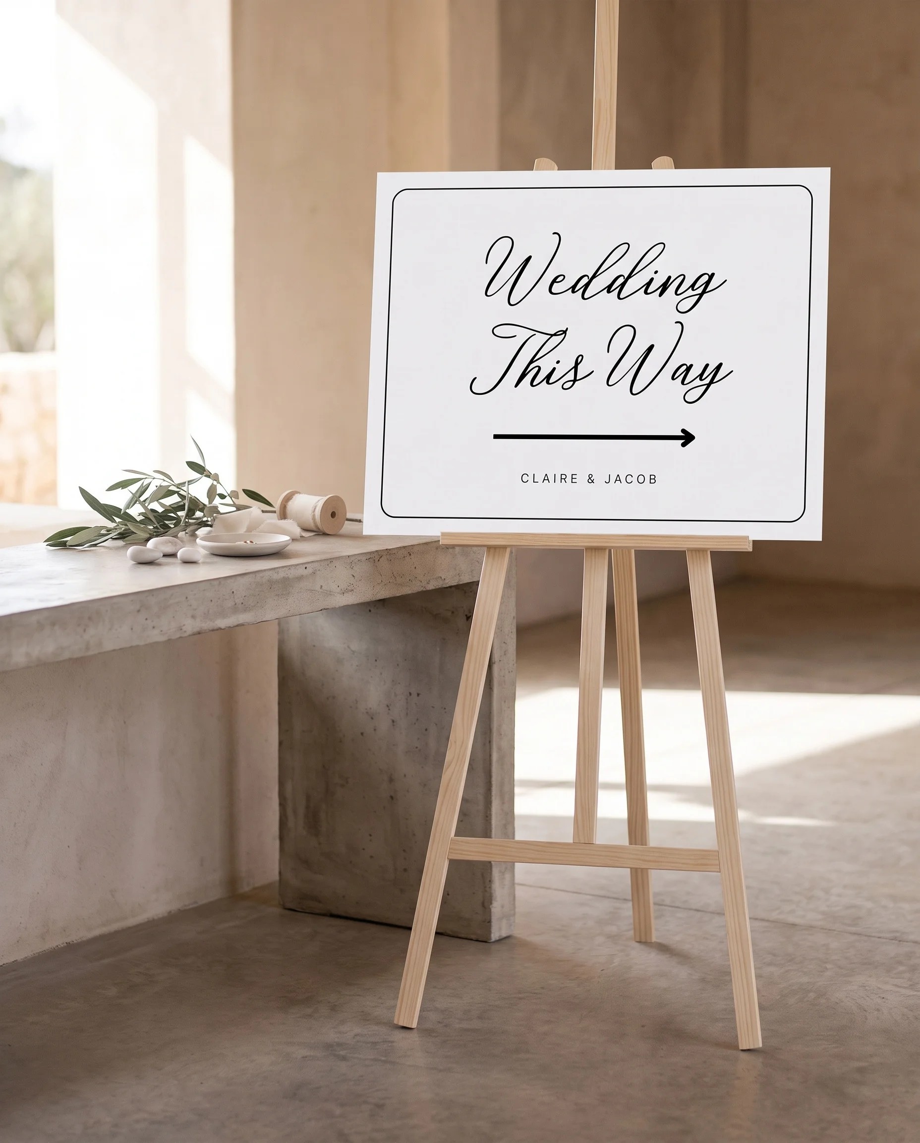 Lyris wedding directional sign — single page shown beside furniture for scale on premium editorial paper under soft natural light, printable wedding signs.