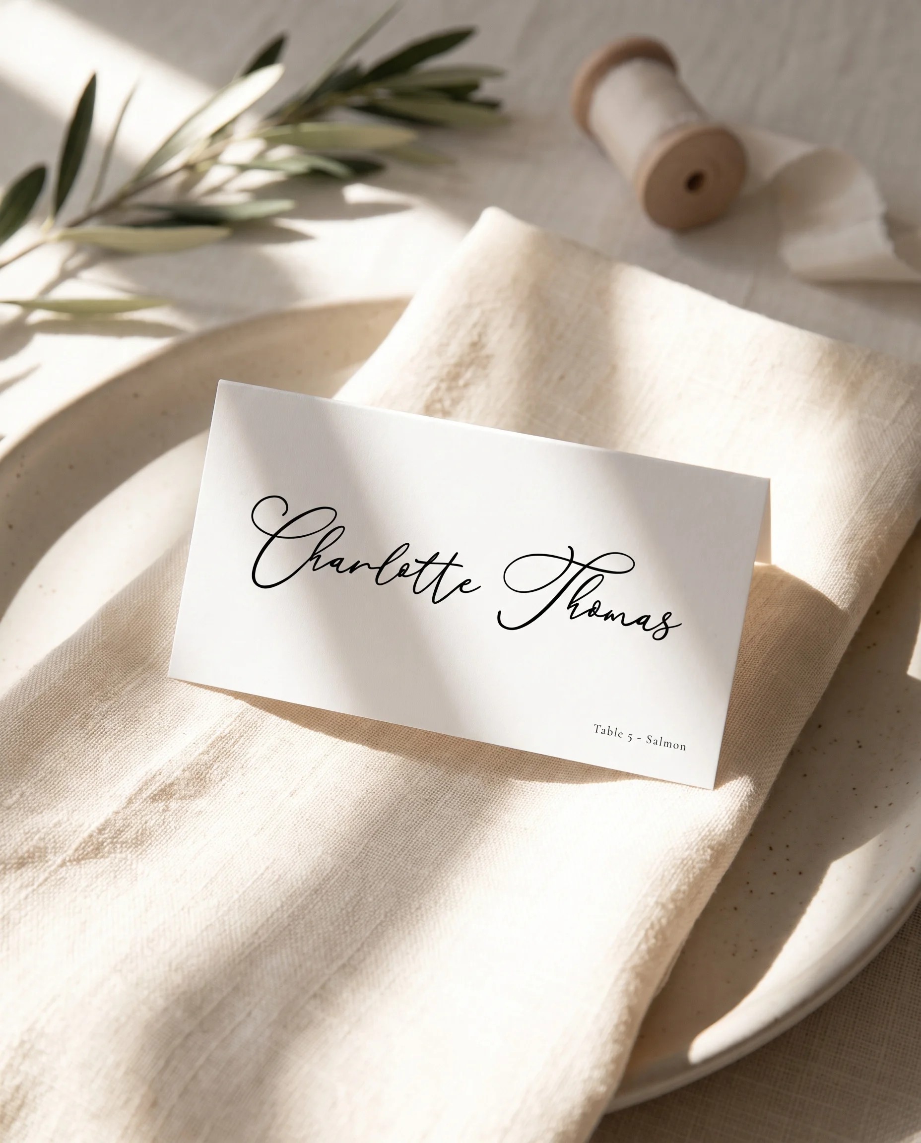Quiet Line wedding place cards — a single card displayed at a set place setting under soft overhead light, wedding name cards.