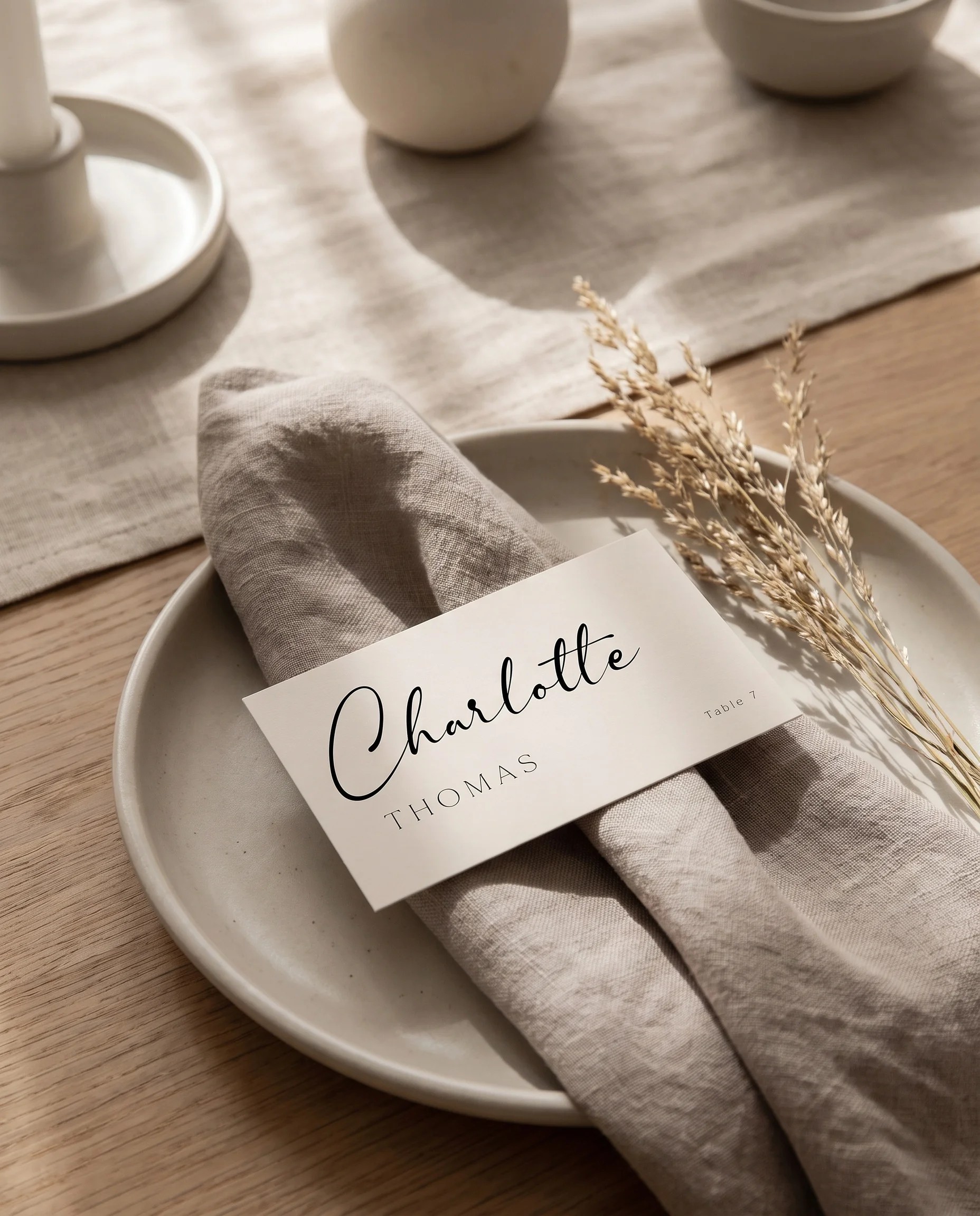 Tassel Arc wedding place cards — a single card displayed at a set place setting under soft overhead light, wedding name cards.