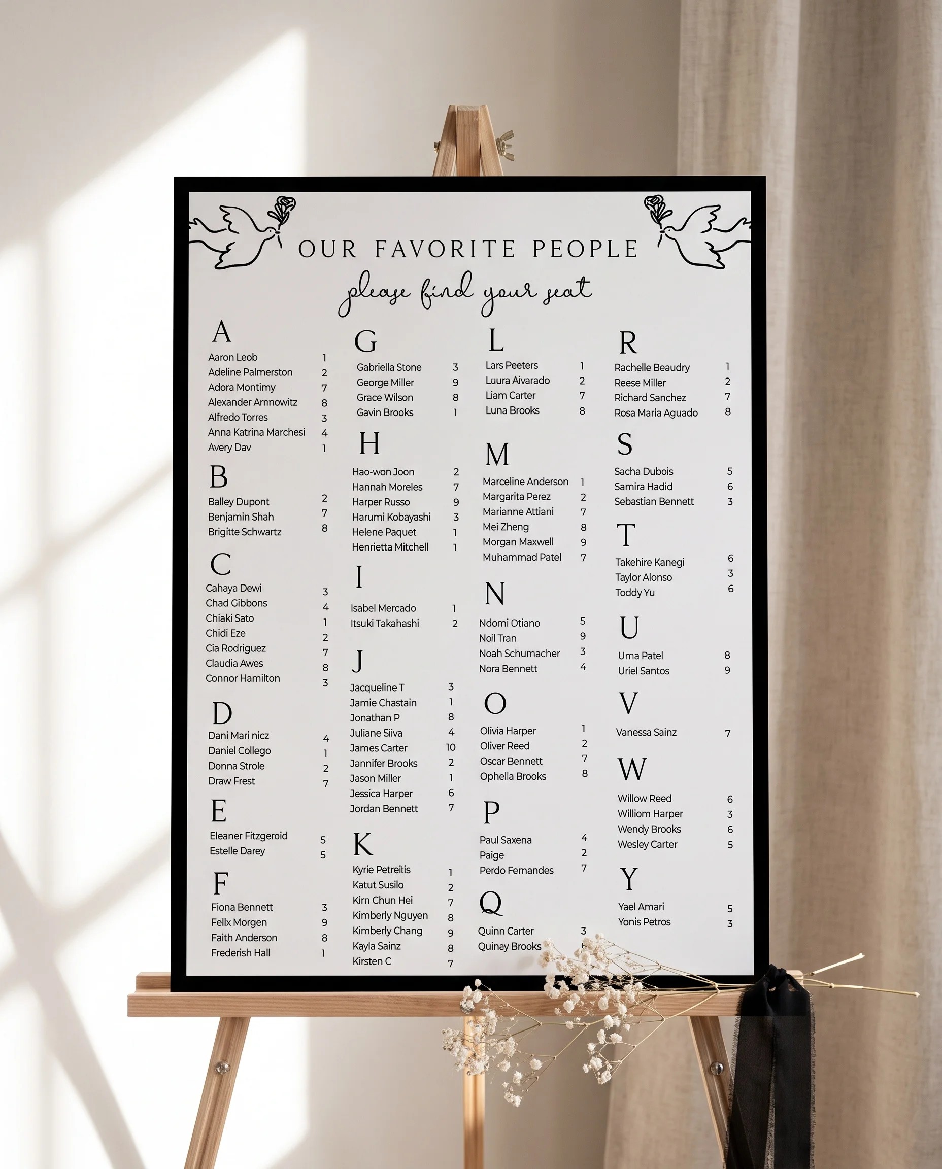 Sketchbook Bow wedding seating chart — displayed on an easel under soft natural light with a slight overhead angle, wedding seating chart