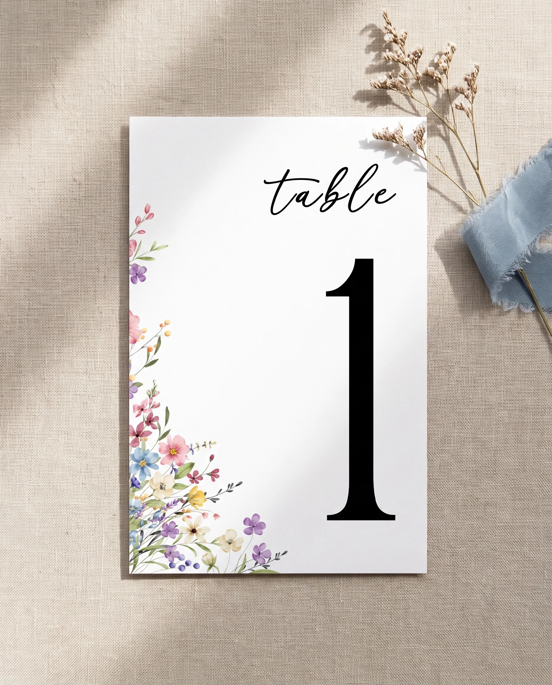 Meadowlark wedding table number — single card lying flat under soft overhead light on premium paper, wedding table numbers