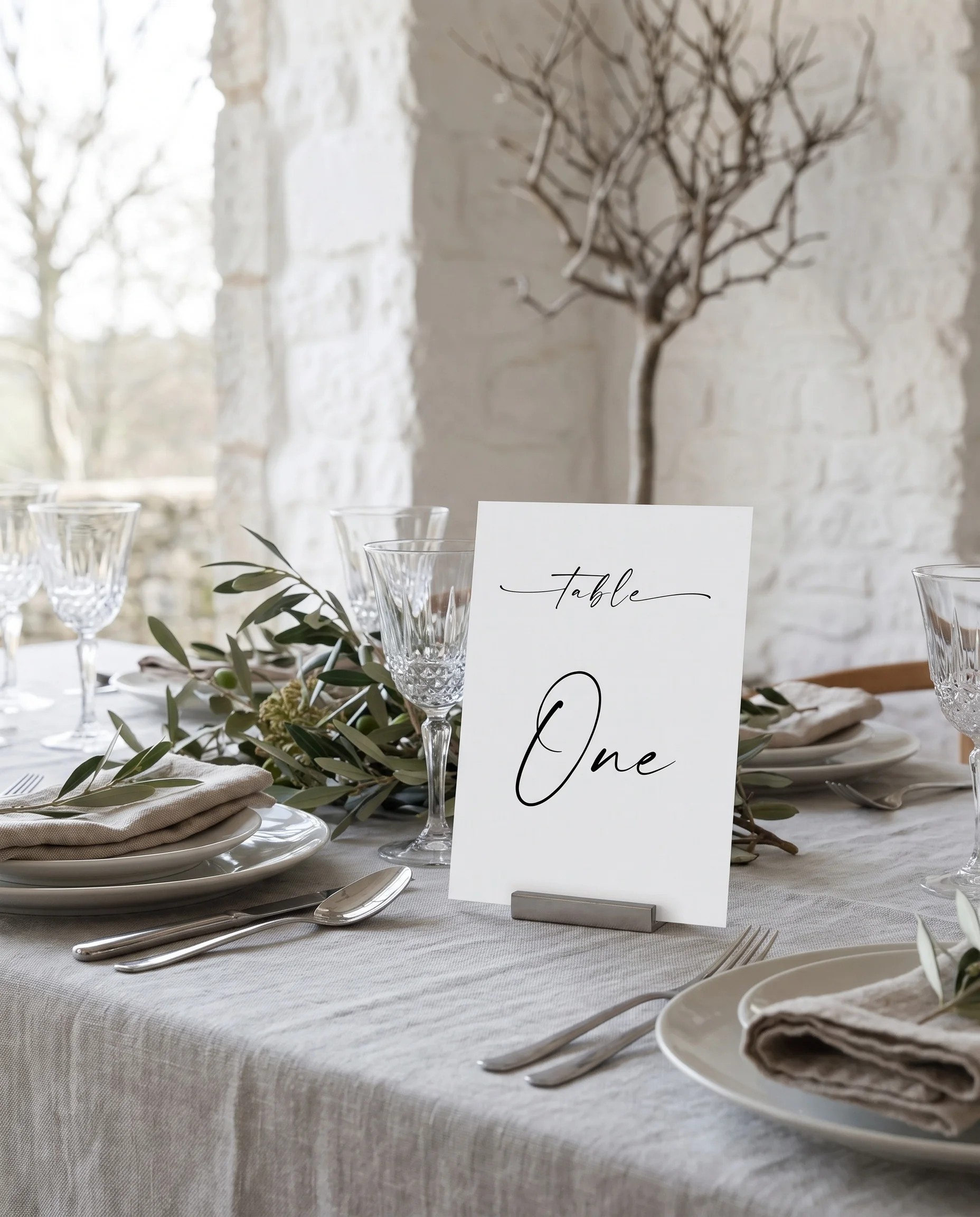 Liminal wedding table number — displayed on a set reception table under soft overhead natural light, table number signs