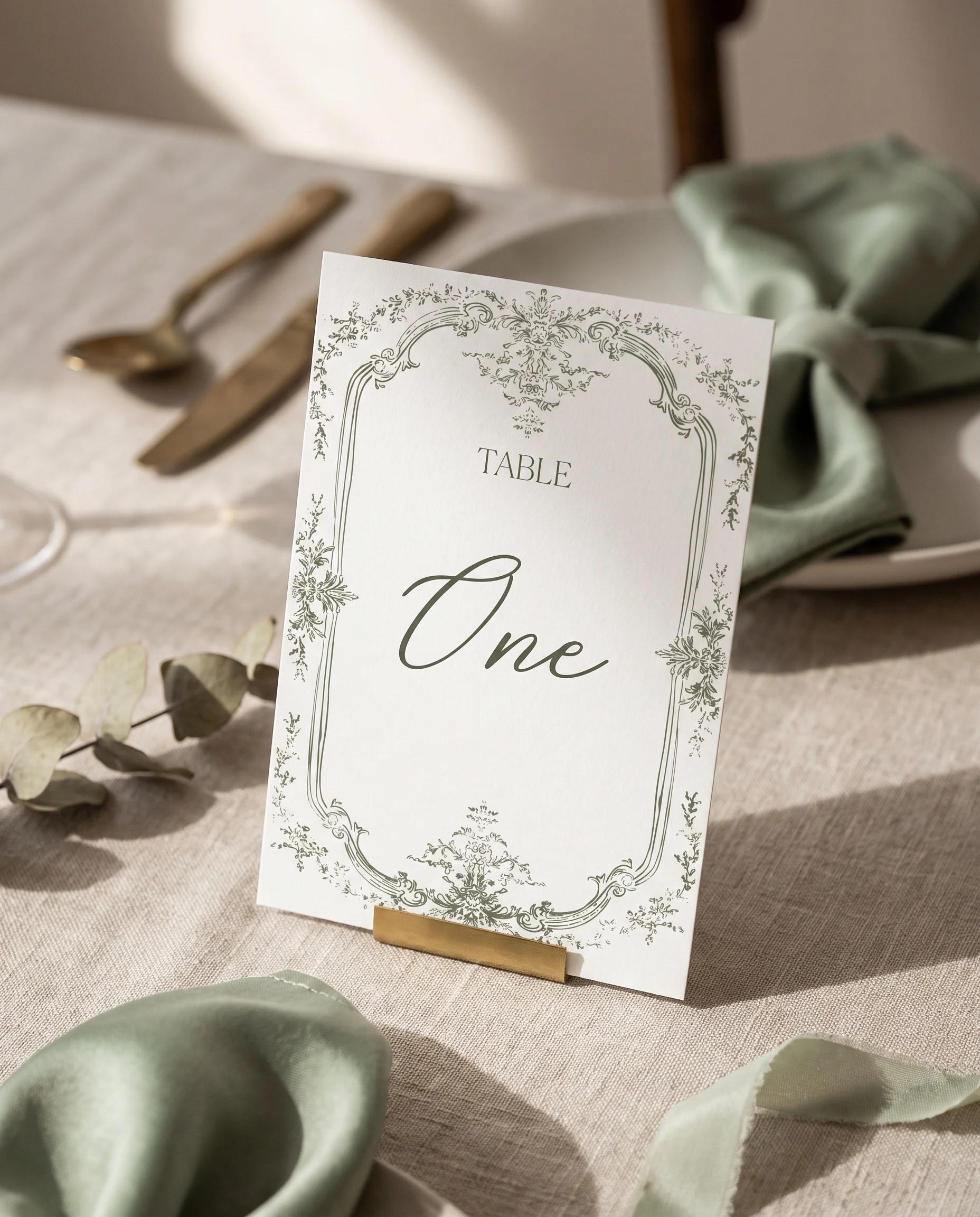Sage Crest wedding table number — standing upright on a dressed table under soft natural light, premium editorial table numbers wedding.